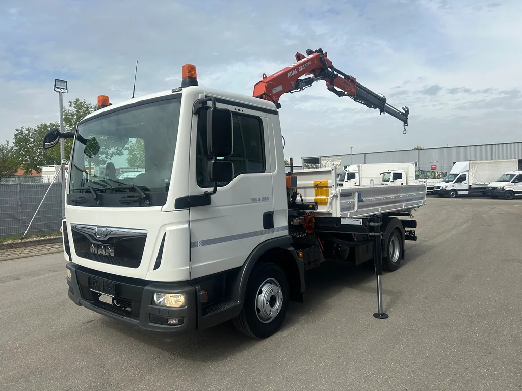 MAN-LKW mit Pritsche und ausgefahrenem Ladekran schräg von vorne.