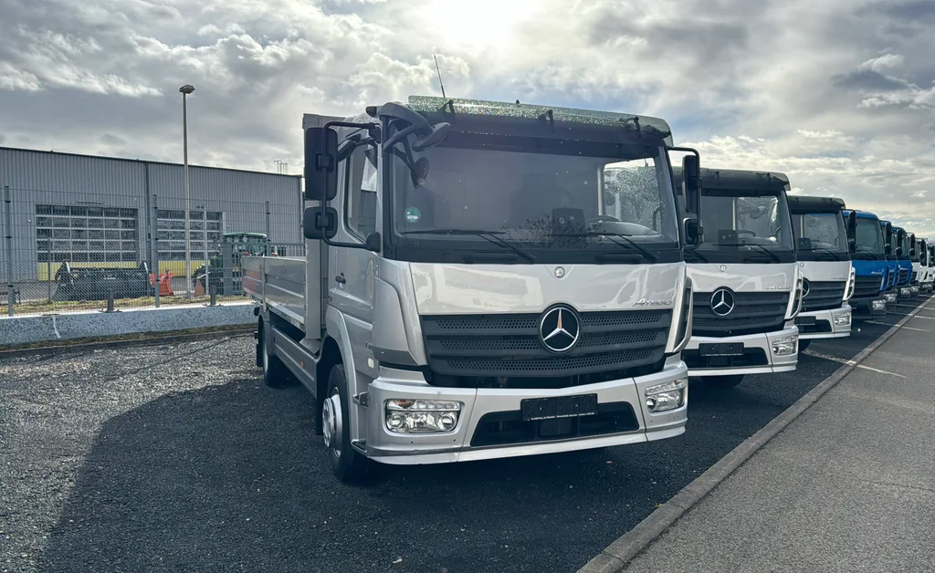 Reihe weißer und blauer Mercedes-LKW auf dem Betriebsgelände.