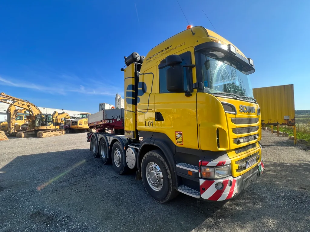 Gelbe vierachsige Scania-Sattelzugmaschine in Dreiviertelansicht.