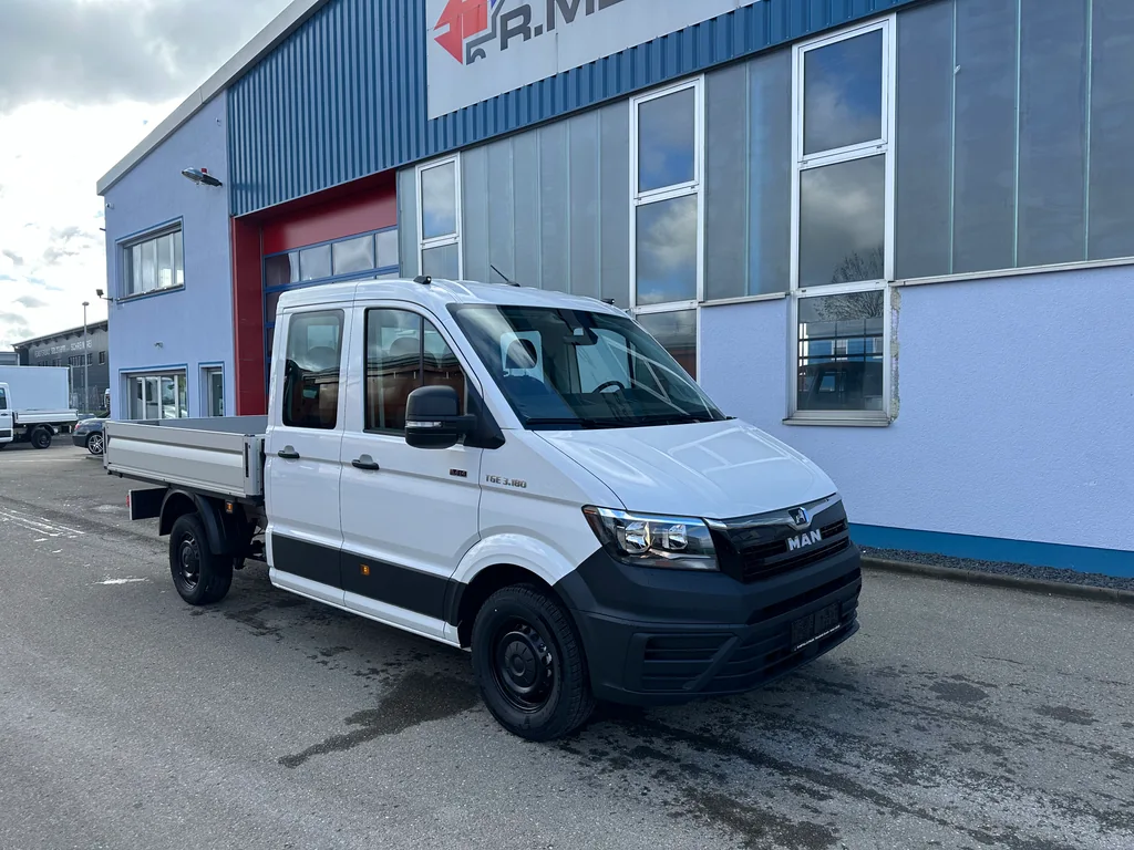 Weißer MAN-Pritschentransporter mit Doppelkabine vor der Firmenhalle.